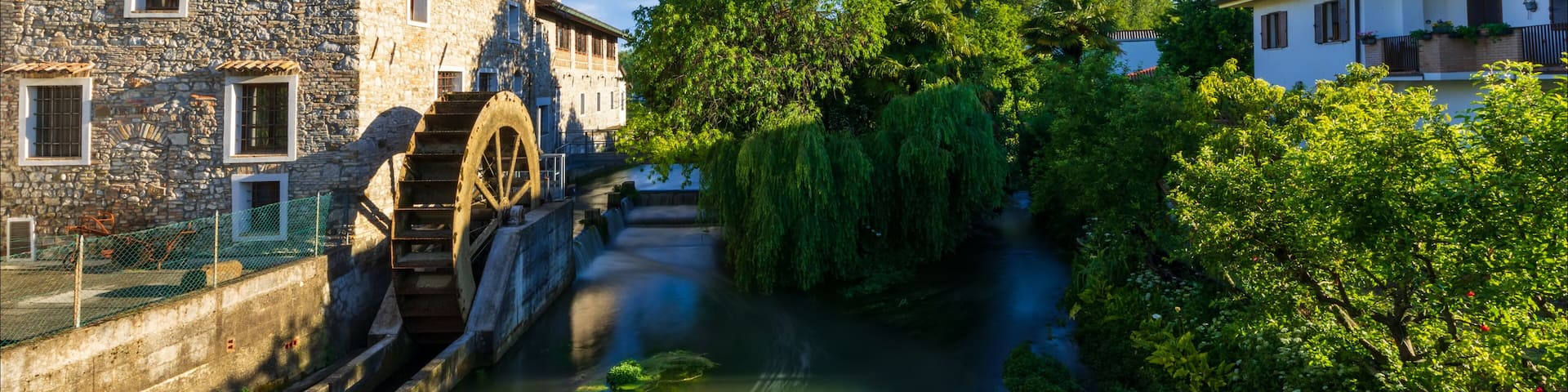 Antico mulino a pale sul fiume nel borgo medievale di Strassoldo. Italia.