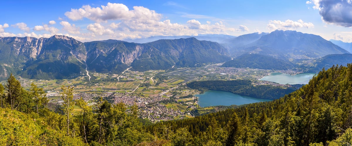 Paesaggio montuoso con una città, un lago e fitte foreste.