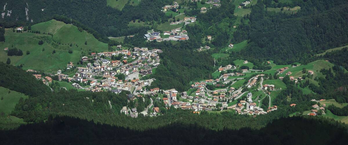 A mountainous village with scattered houses and dense forests.