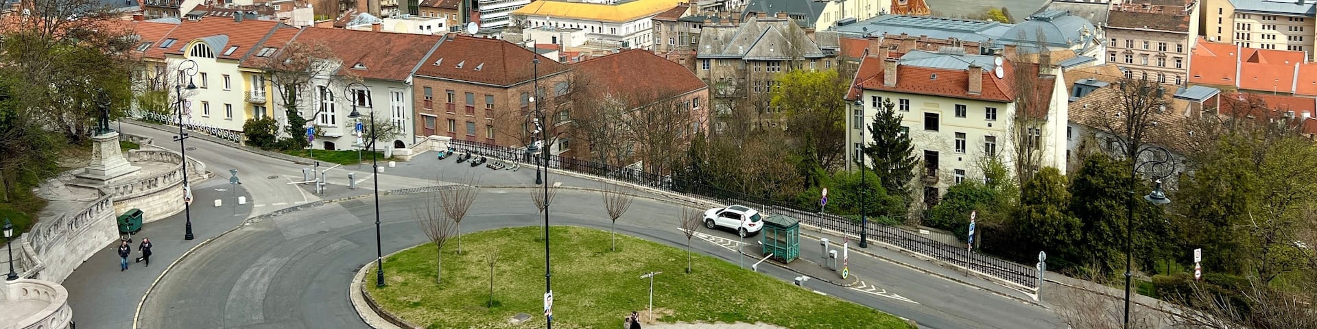 A panoramic view of a city with a river, historic buildings, and a prominent church with a tall spire.