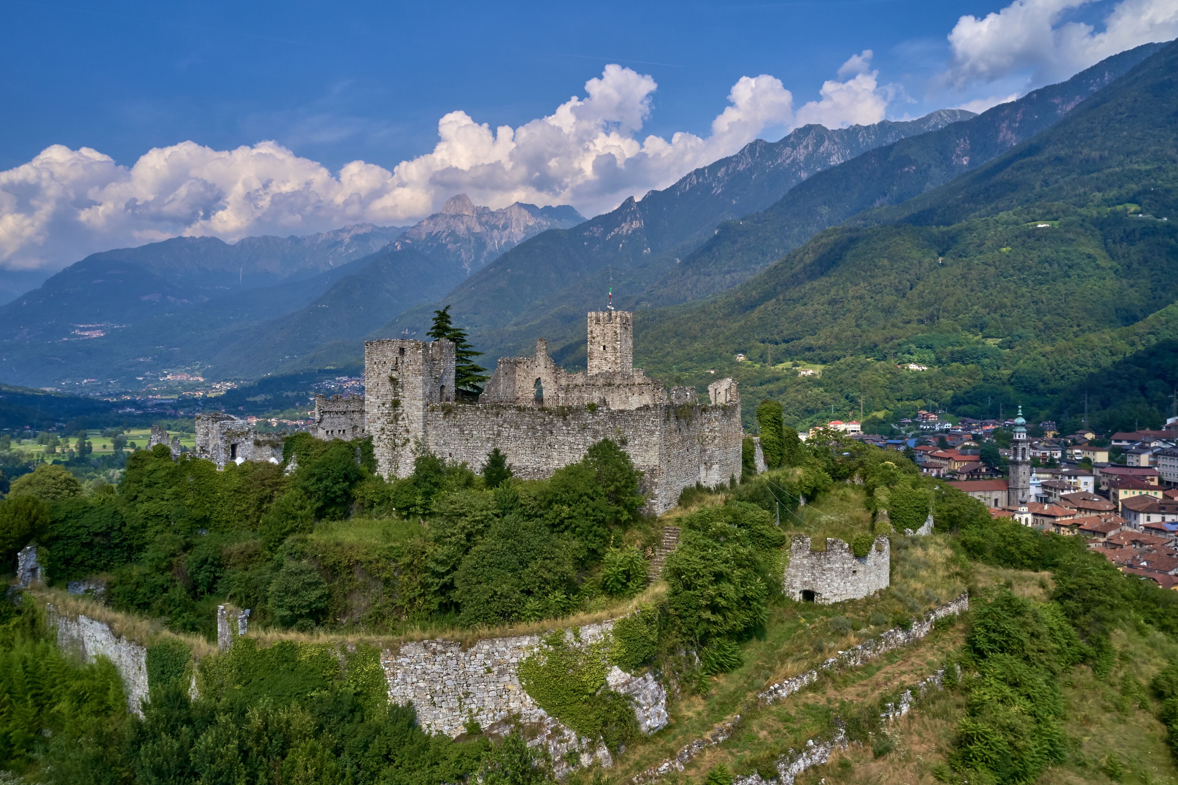 Aerial photography, castle of Breno in the province of Brescia, Lombardy region. The castle is located on a mountain surrounded by the Alps in the background the city of Breno in the north of Italy.