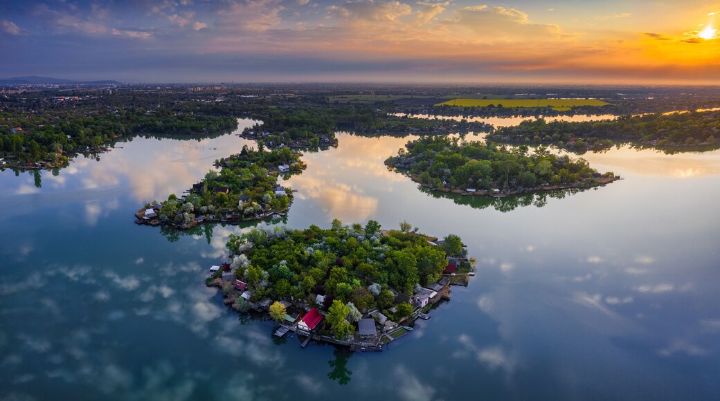 Budapest, Hungary - Aerial view of Lake Kavicsos (Kavicsos to) of Csepel district with small fishing islands on it. Fishing huts, piers and cabins on the islands. Warm sunrise and reflecting clouds.