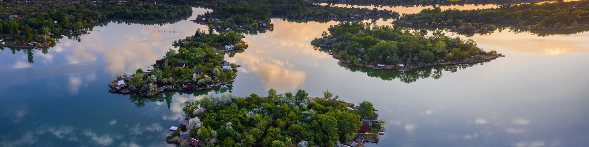 Budapest, Hungary - Aerial view of Lake Kavicsos (Kavicsos to) of Csepel district with small fishing islands on it. Fishing huts, piers and cabins on the islands. Warm sunrise and reflecting clouds.