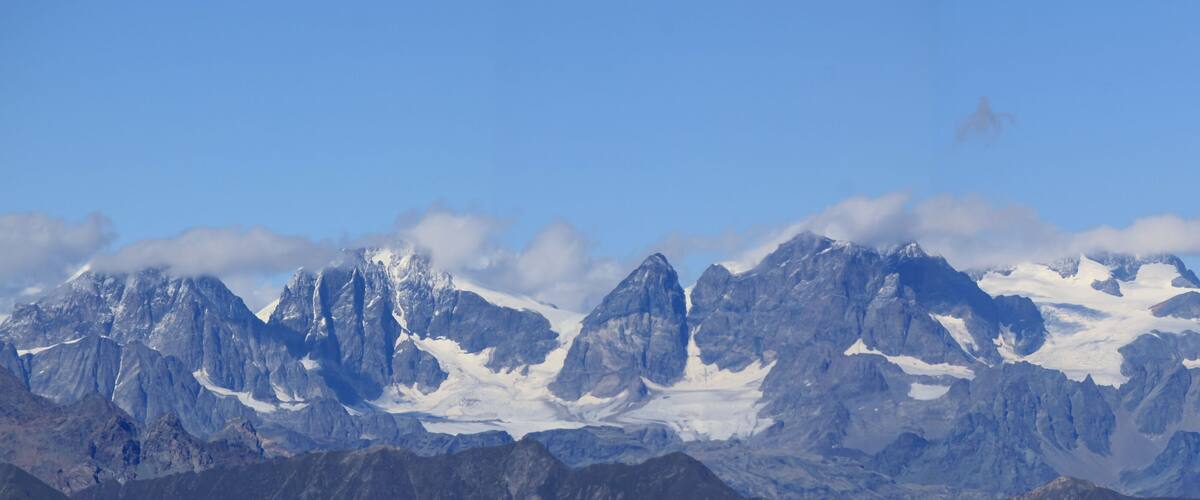 A range of rugged mountains with snow-capped peaks under a clear blue sky.