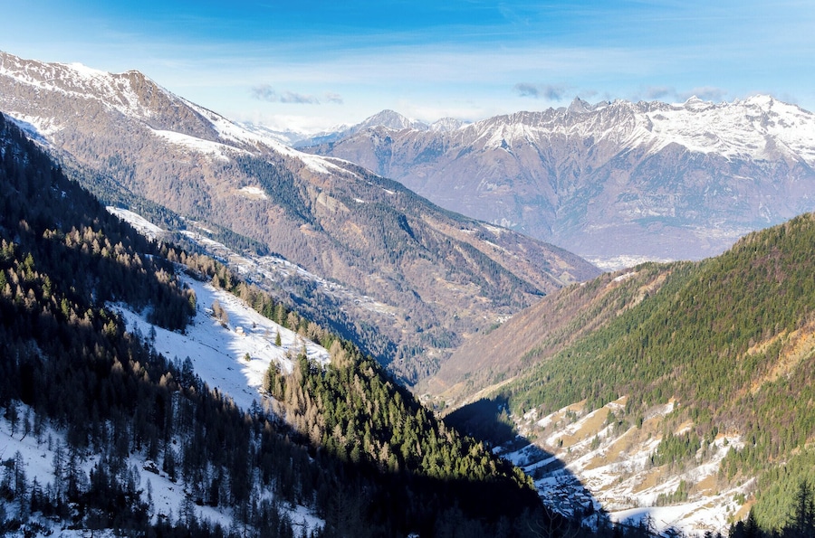 Un paysage montagneux aux sommets enneigés et aux forêts denses.