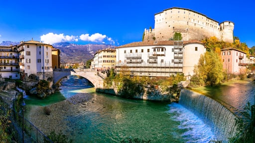 A river flowing through a town with historic buildings and a castle.