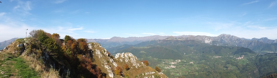 Paisaje montañoso con afloramientos rocosos y un valle con edificios dispersos.