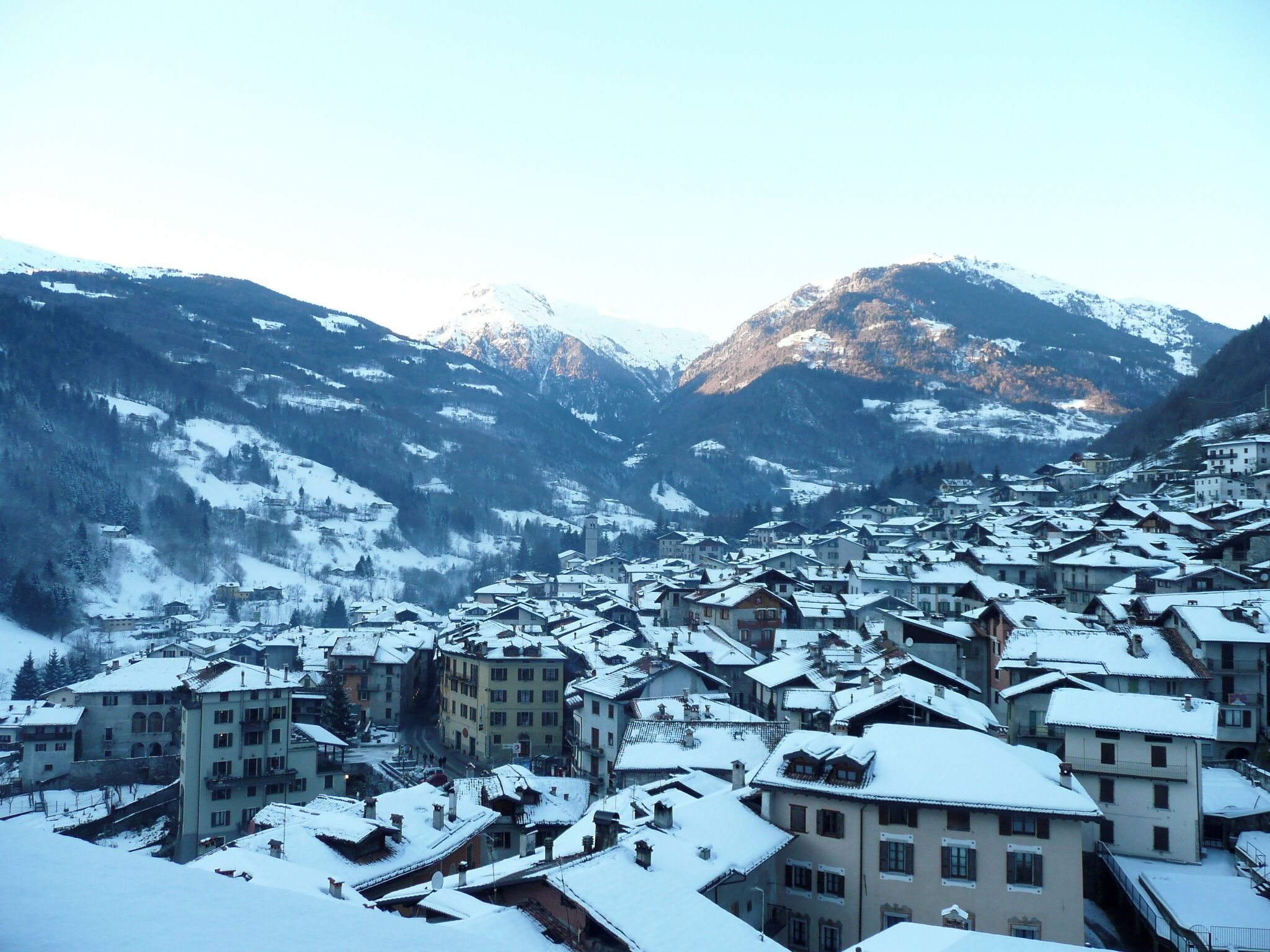 A snow-covered village nestled in a valley with mountains in the background.