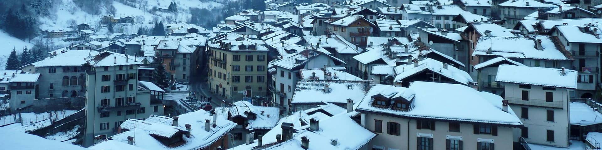 A snow-covered village nestled in a valley with mountains in the background.