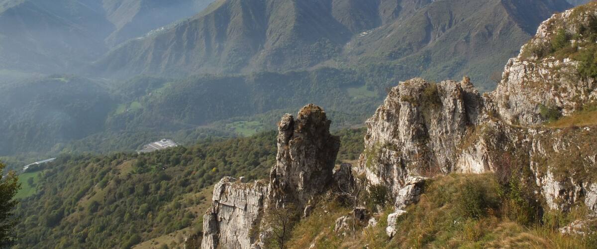 A mountainous landscape with rocky outcrops and dense greenery.