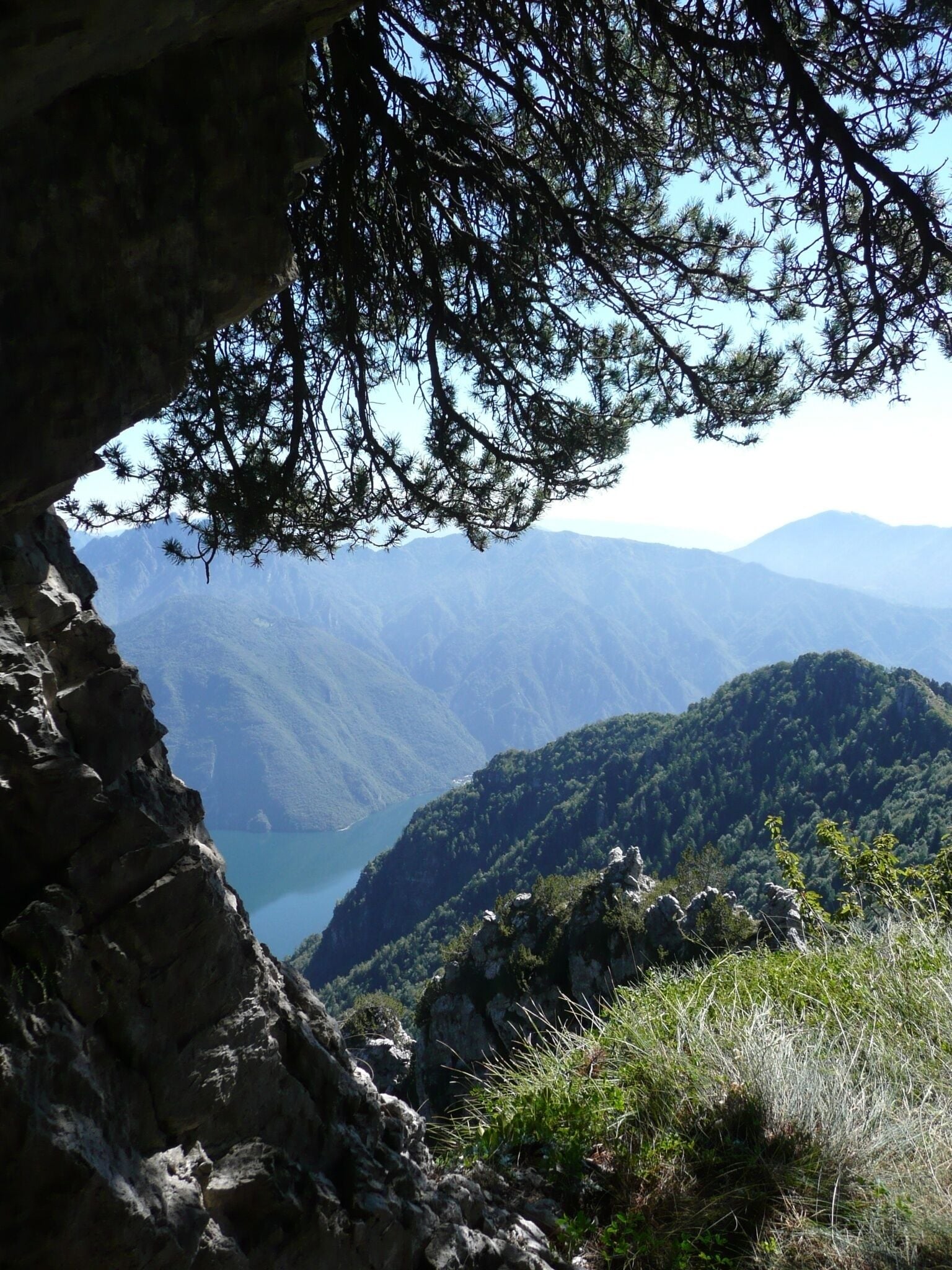 Paesaggio montuoso con uno sfondo roccioso e una valle all'orizzonte.