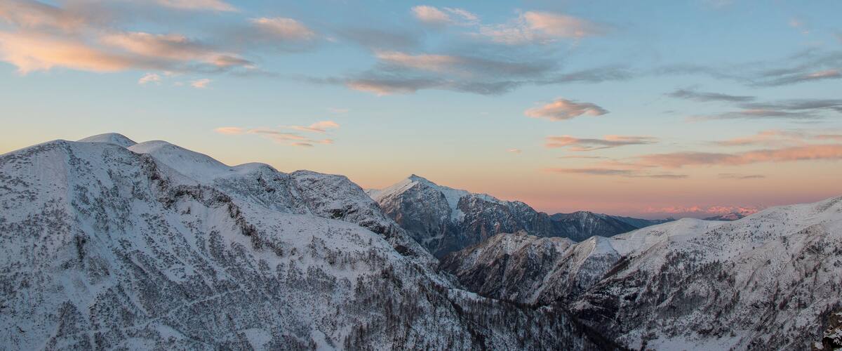 A snow-covered mountain range with a clear sky and a sunset.