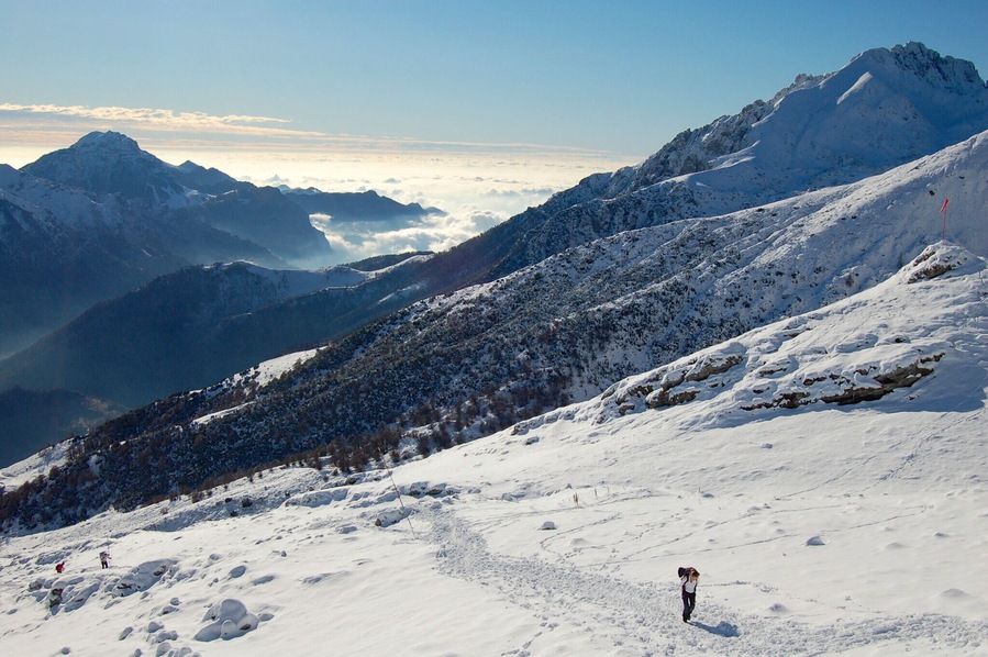 Paisaje montañoso cubierto de nieve, con cielo despejado y nubes distantes.