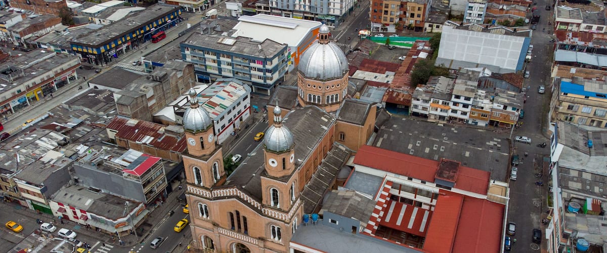 An aerial view of a city with a prominent church with a large dome and clock tower, surrounded by various buildings and streets.