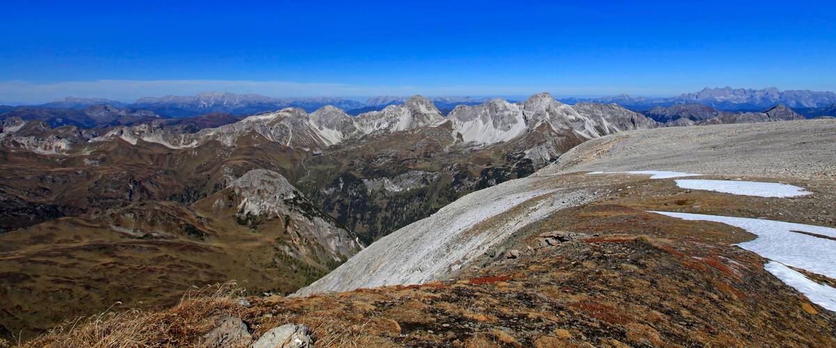A mountainous landscape with snow patches and rocky terrain.