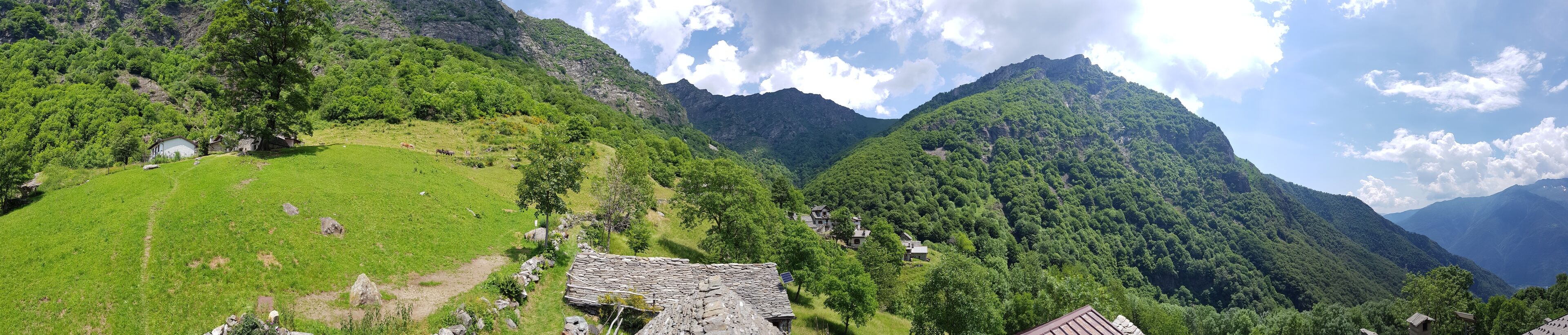 A mountainous landscape with green fields, a stone house, and a small building.