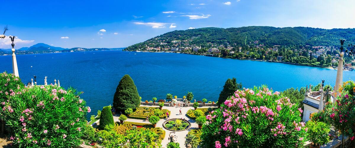 A coastal landscape with a large body of water, green hills, and statues.