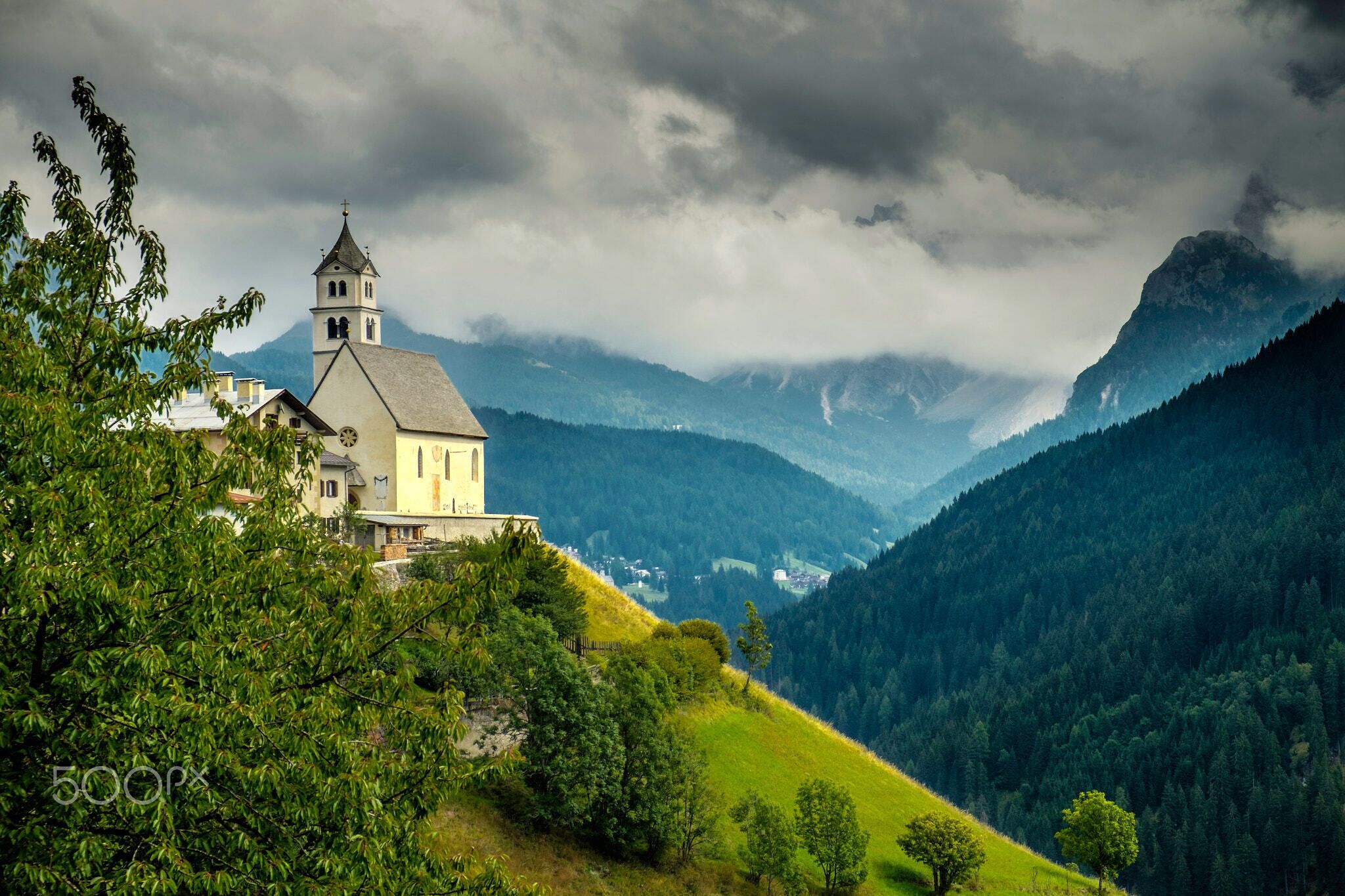 A church on a hill with a mountain backdrop.