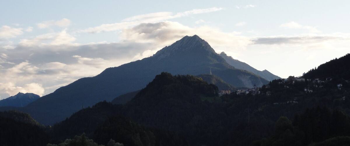 A mountain range with a prominent peak, a calm lake, and a small island.