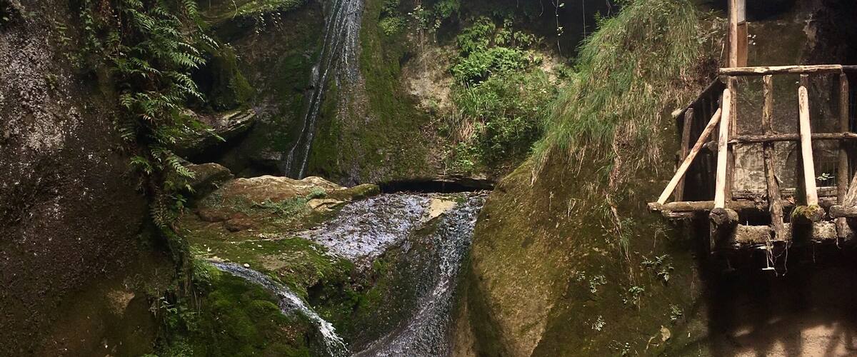 A waterfall cascading over moss-covered rocks in a forested area.
