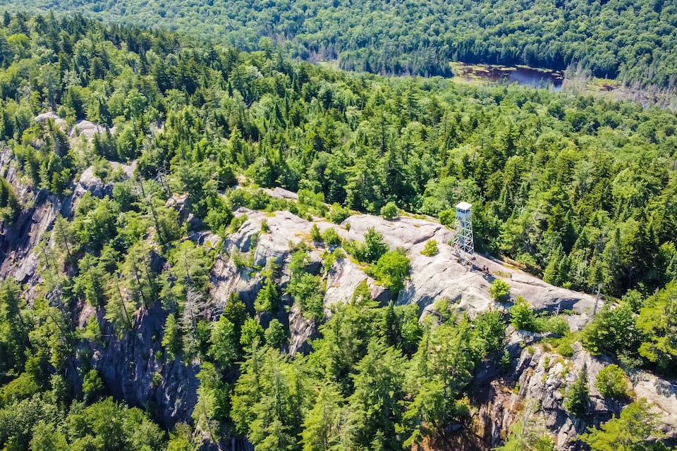A forested mountain with a rocky outcrop and a lookout tower.
