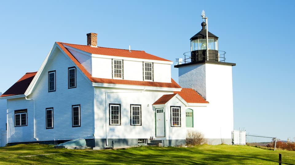 A white house with a red roof and a lighthouse.