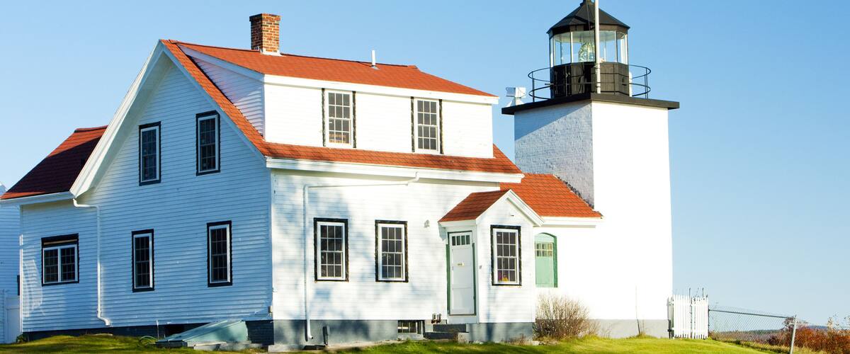 A white house with a red roof and a lighthouse.