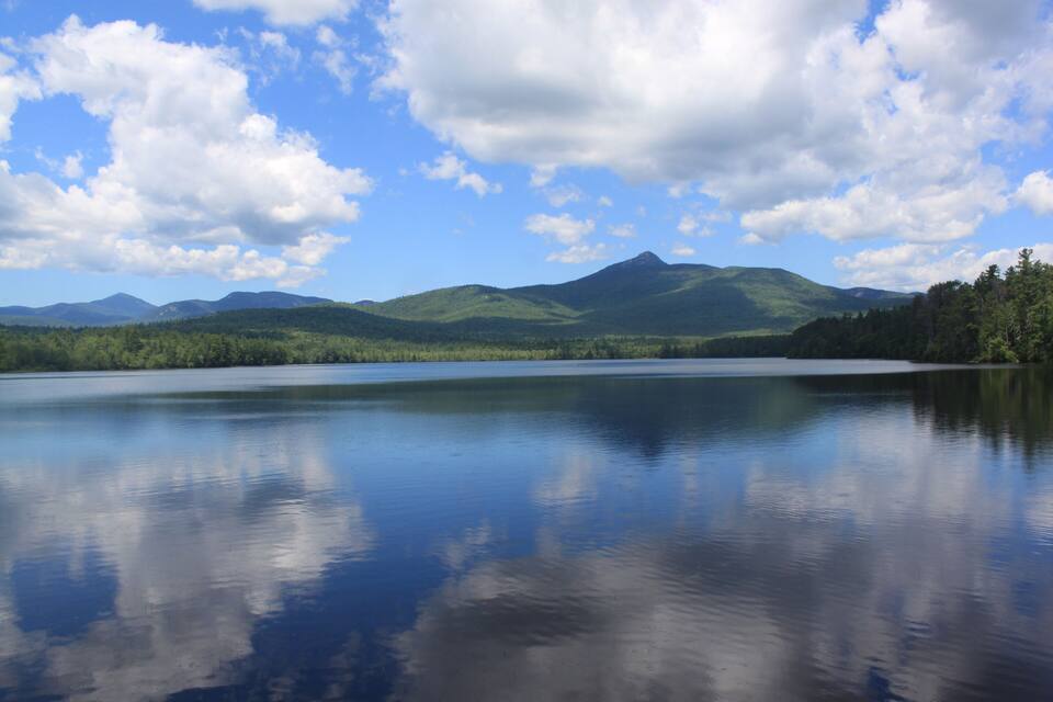 A calm lake with mountains in the background and a clear sky.