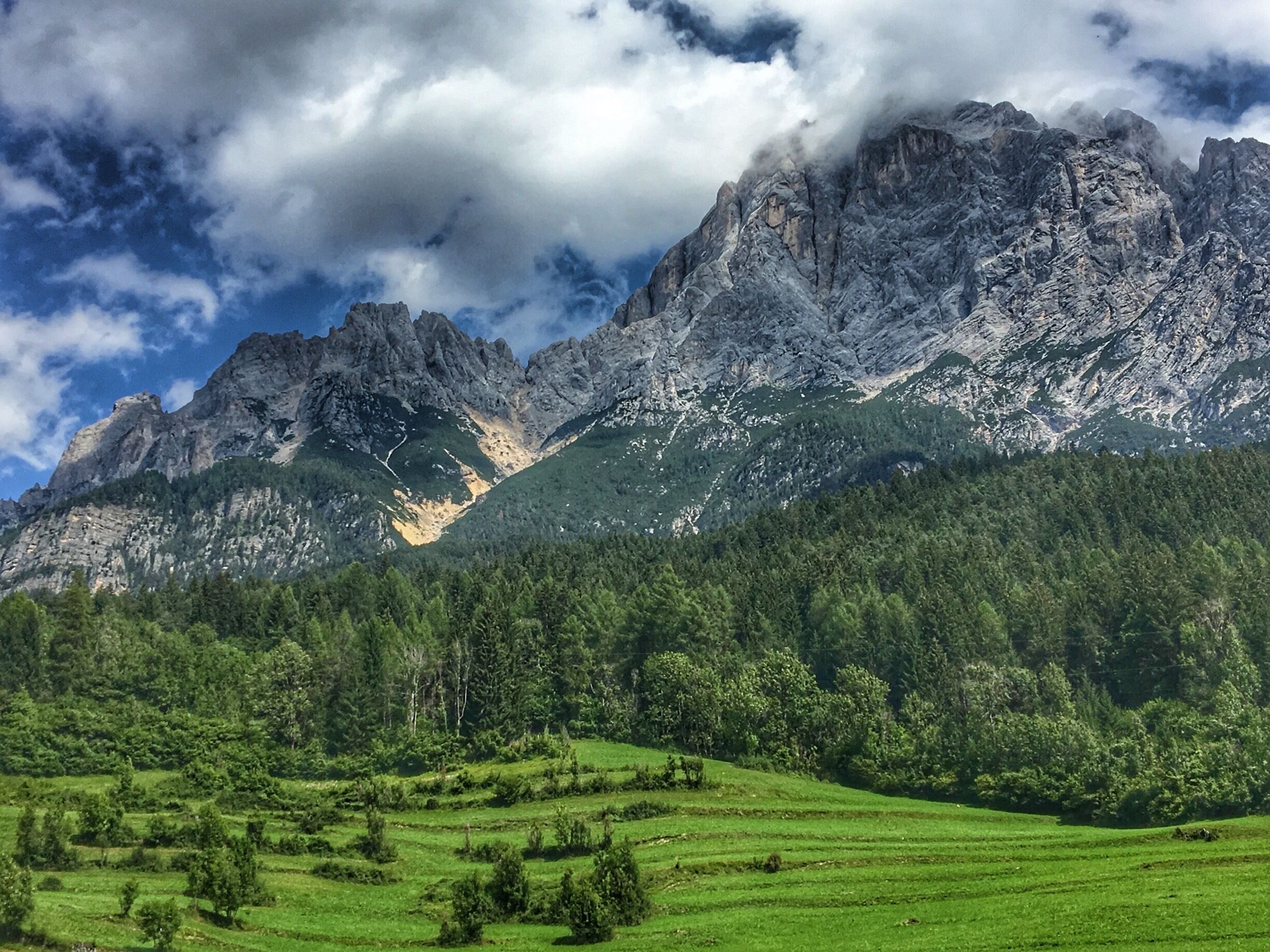 A mountainous landscape with rugged peaks, dense forest, and terraced fields.