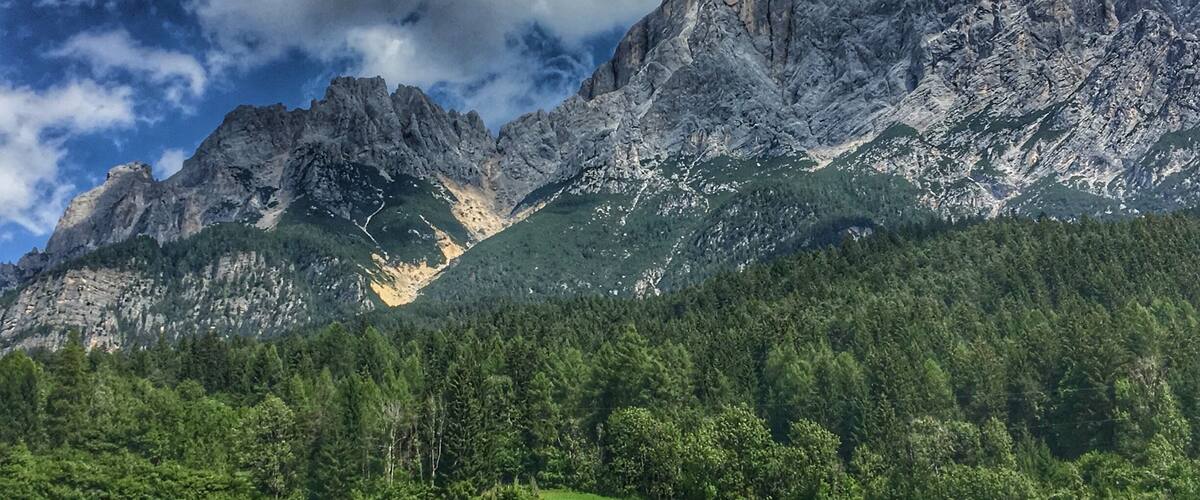 A mountainous landscape with rugged peaks, dense forest, and terraced fields.