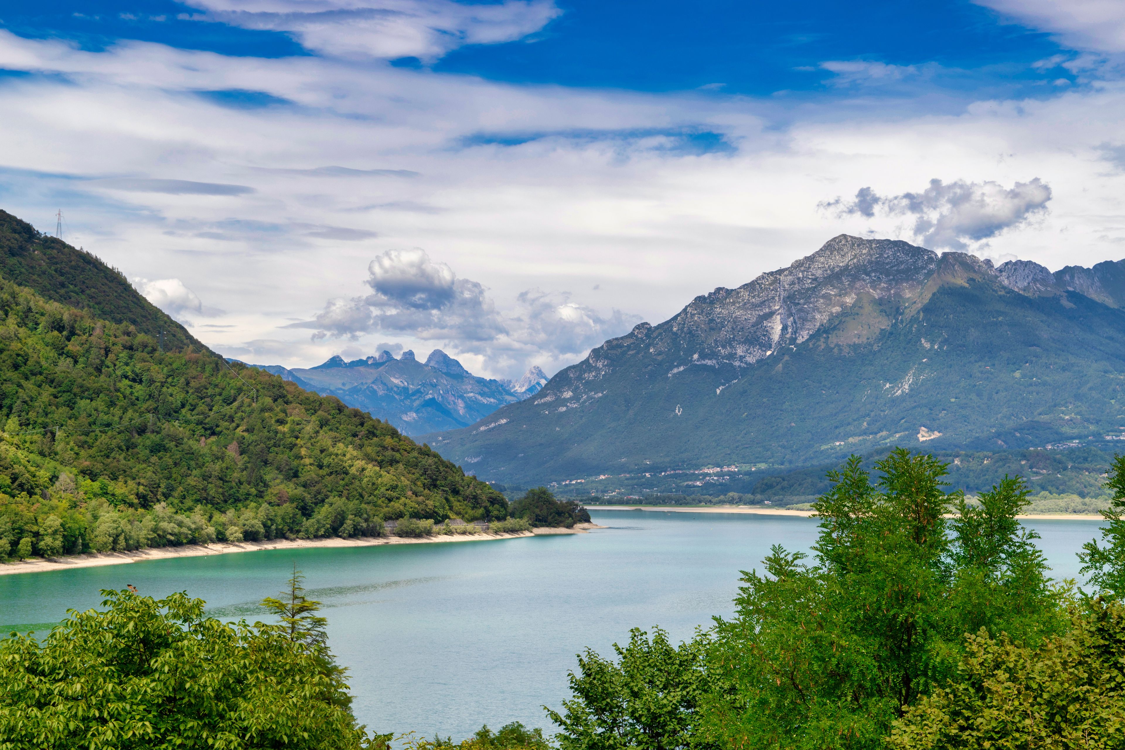 Un lac entouré de montagnes, une plage et une végétation luxuriante.