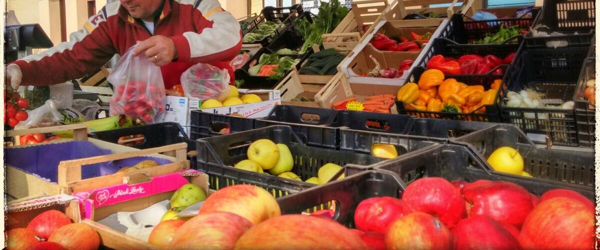 A fruit market with various fruits like apples, oranges, and tomatoes displayed in crates.