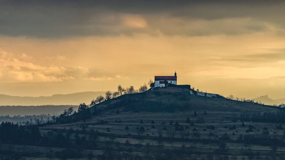 A solitary house on a hill with a cloudy sky.