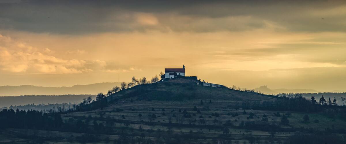 A solitary house on a hill with a cloudy sky.