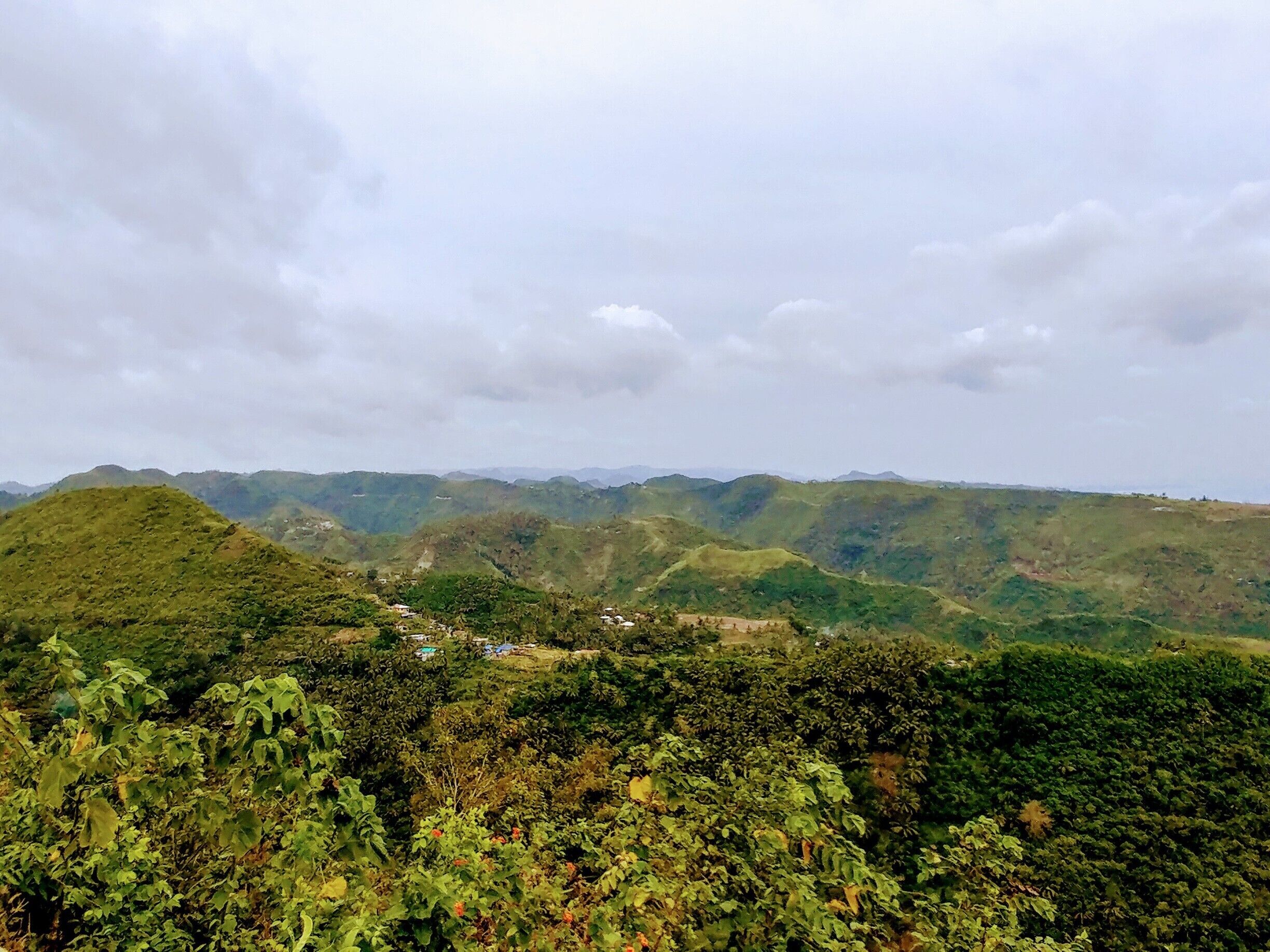 A mountainous landscape with lush greenery and scattered buildings.