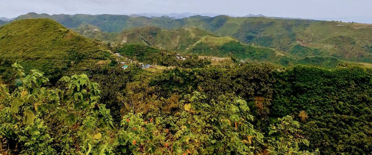 A mountainous landscape with lush greenery and scattered buildings.