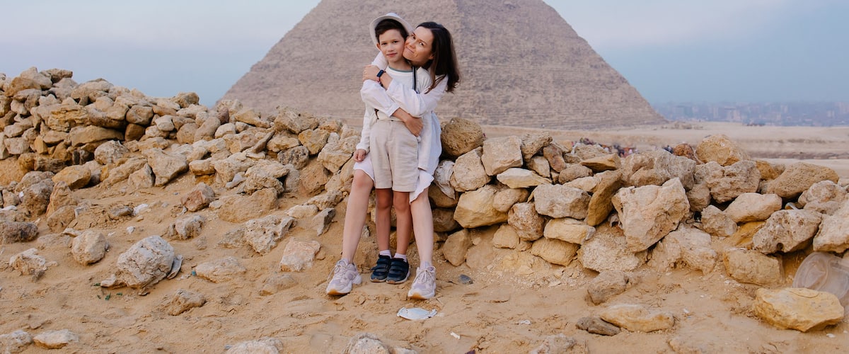 Eine Pyramide, felsiges Gelände und eine Person, die eine andere umarmt.