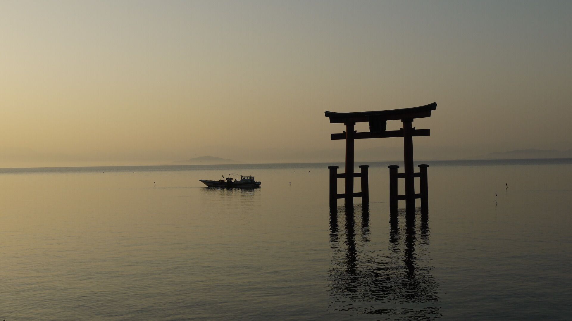 A serene lake with a traditional Japanese torii gate in the foreground and a small boat in the distance.