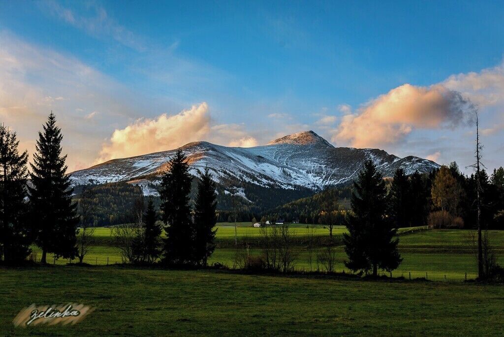A snow-capped mountain with a clear sky and a few clouds.