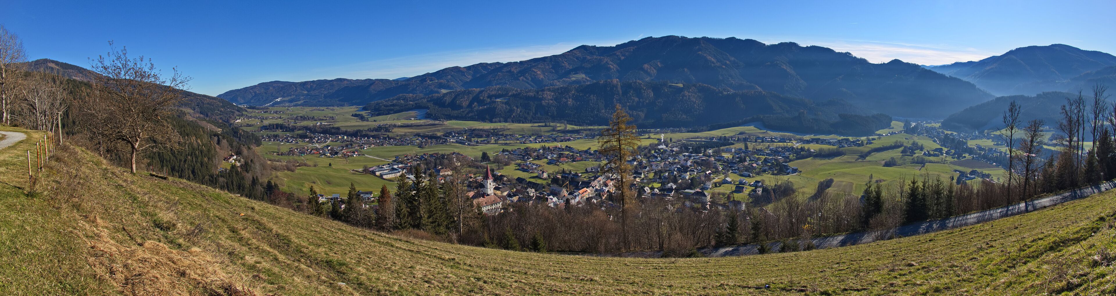 A valley with a town nestled among green hills and mountains.