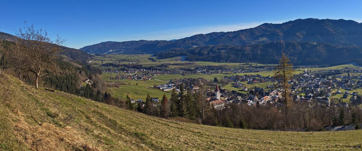A valley with a town nestled among green hills and mountains.