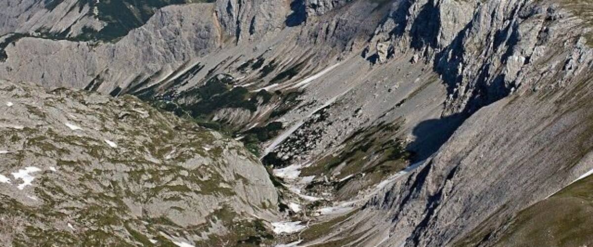A rugged mountain landscape with steep slopes and patches of snow.