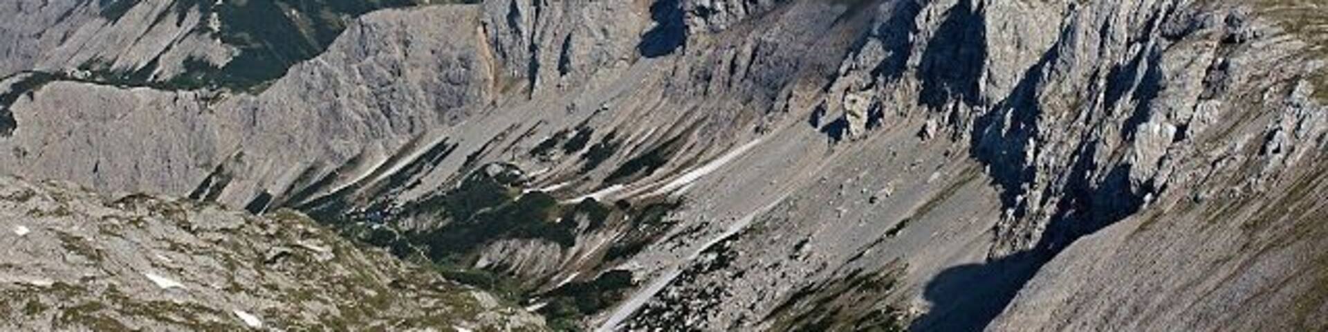 A rugged mountain landscape with steep slopes and patches of snow.