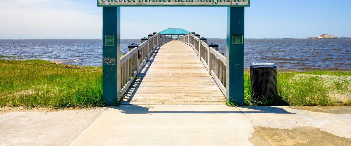 A pier leading to Chester M. McPhearson Jr. Pier with a view of the water and distant buildings.