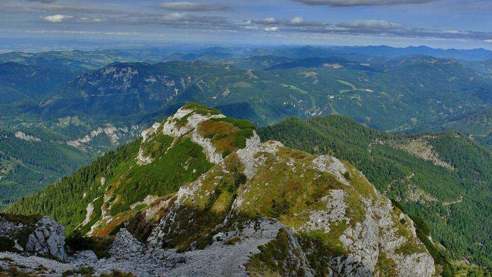 A mountainous landscape with a prominent rocky peak covered in greenery.