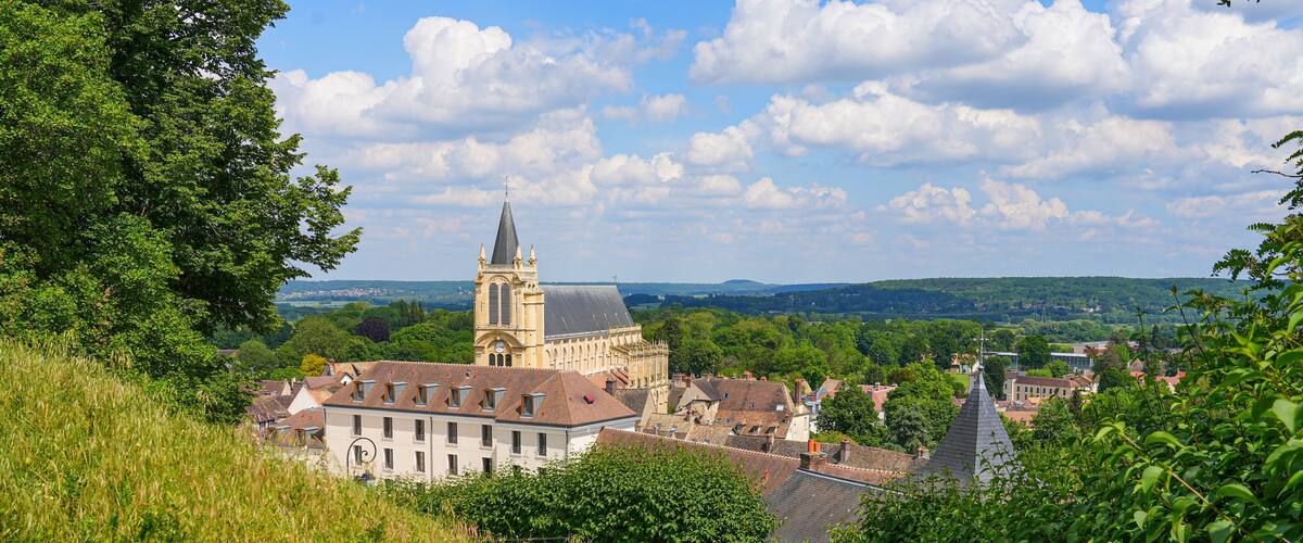 A town with a prominent church tower, lush greenery, and a hillside path.