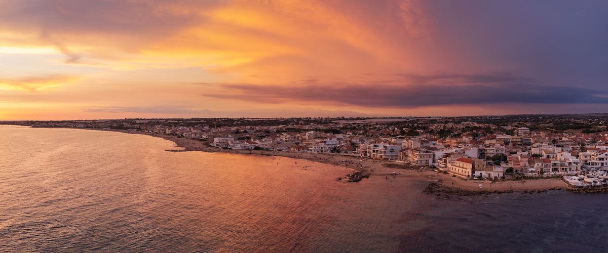 A coastal town with a beach and houses along the shoreline.
