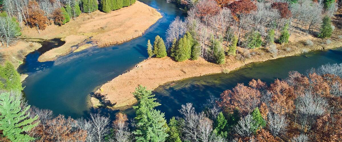 A river winding through a forest with autumn-colored trees.