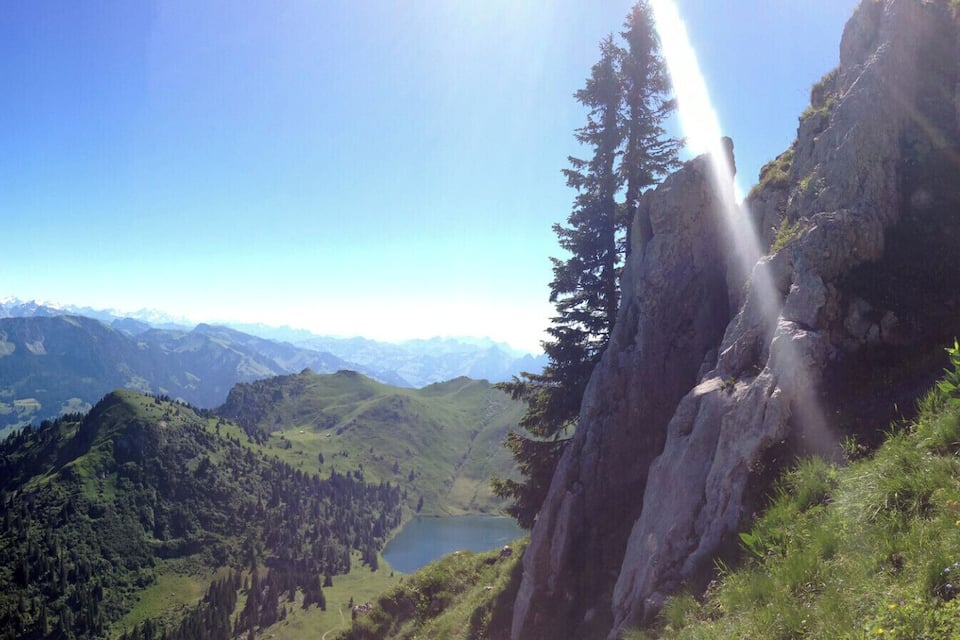 A mountainous landscape with a lake, a waterfall, and a clear blue sky.