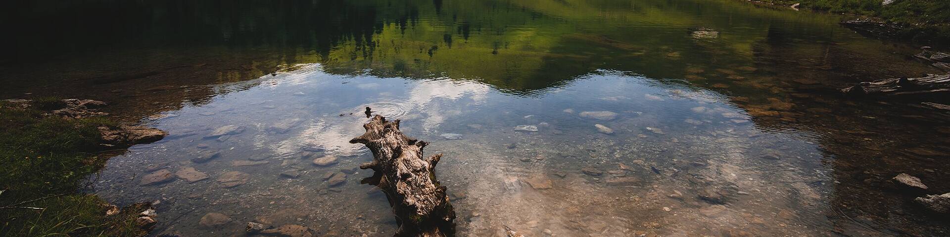 One of the mountain lakes in Stockhorn, beautiful and calm during the sunny day, two wooden benches are on site to provide the hikers a place to rest and eat their picnic.